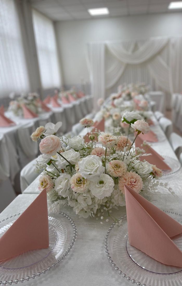 Festtafel mit Blumengesteck, rosa Servietten und Platztellern mit Perlenrand